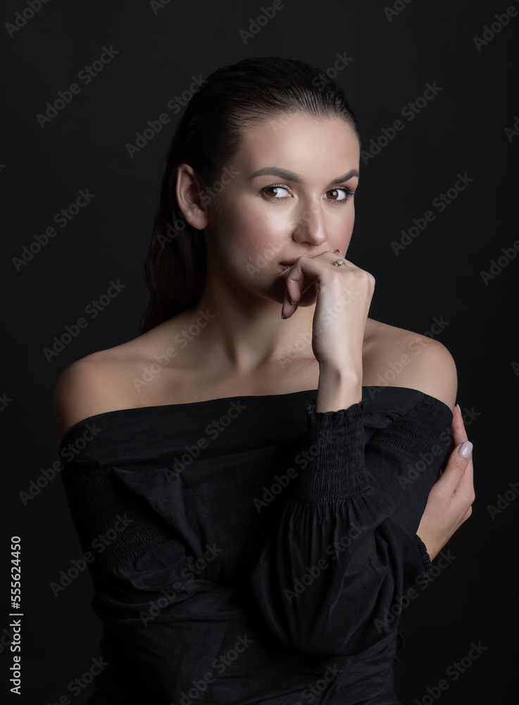 Studio portrait of beautiful and sexy brunette woman with wet hairstyle, make-up and black blouse. Model looking at camera and thinking by holding hand palm near mouth Studio portrait of beautiful and sexy brunette woman with wet hairstyle, make-up and black blouse. Model looking at camera and thinking by holding hand palm near mouth