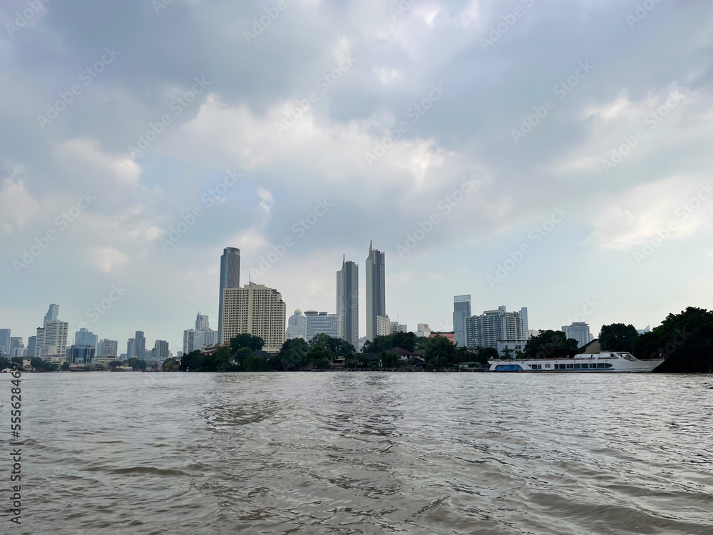 Bangkok. Krung Thep Maha Nakhon. Khlong San district of capital of Thailand. Big modern urban city. View from the Chao Phraya River to the buildings, skyscrapers. Beautiful sunset on the sky. Clouds. 