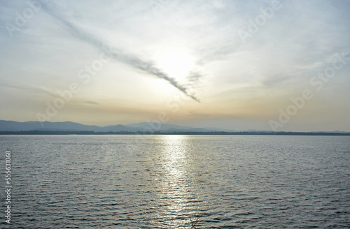 Beautiful cloud line on sky over water surface in evening time. © Taweesak