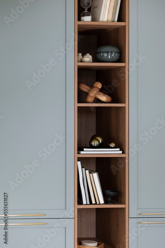 Minimalist composition of living room interior with wooden and blue bookcase, sculpture, books, glass balls, simple casket and personal accessories. Home decor. Template.