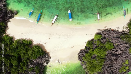 Tropical beach with tourists surrounded by blue water, aerial view. Lahos Island, Caramoan Islands, Philippines. Boats and tourists on the beach. Summer and travel vacation concept. photo