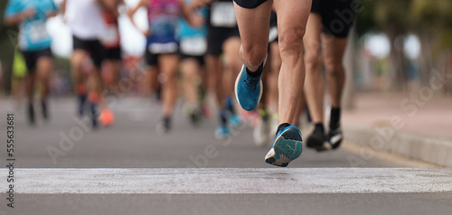 Maratończycy biegający po drogach miejskich, duża grupa biegaczy