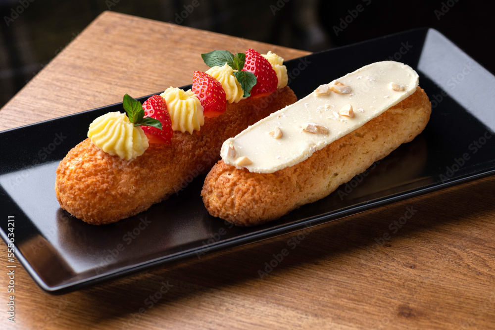 Eclair made with cream and hazelnut in plate on a wooden table. Healthy food Eclair made with cream and hazelnut in plate on a wooden table. Healthy food