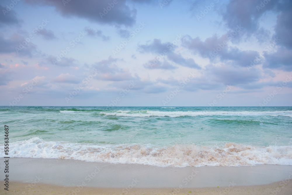 landscape at the sea in the evening. green sea water. waves washing the shore. stormy weather forecast