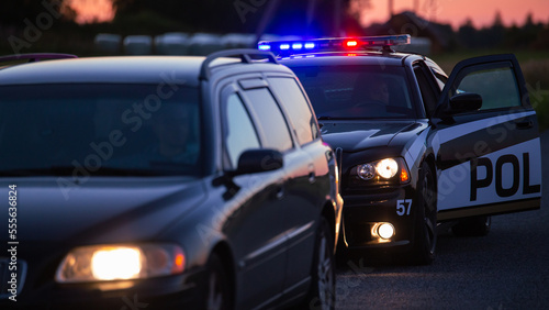 Highway Traffic Patrol Car Pulls over Vehicle on the Road. Male Police Officer Approaches and Asks Driver for License and Registration. Officer of the Law doing Job Professionally. Cinematic Wide Shot