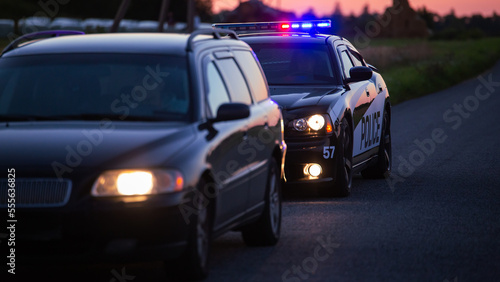 Highway Traffic Patrol Car Pulls over Vehicle Check on Empty Road. Police Officer Comes out of Car and Person for License and Registration, writes a Ticket. Cinematic Wide Angle Side View Shot