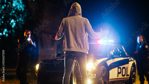 Two Police Officers Aim at a Civilian. Police Using a Weapon Against a Non-Violent Person. Camera Focus on Suspect Raising Hands in Compliance. Escalated Situation due to Police Brutality photo