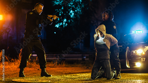 Photos Black Female Police Officers Handcuffing a Compliant Suspect While her Male Partner Intimidats and Threatens the Criminal by Aiming a Gun at Him