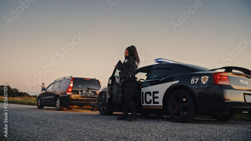 Canvas-taulu Black Female Police Officer Stepping Out of Patrol Car and Heading Towards a Pulled over Car