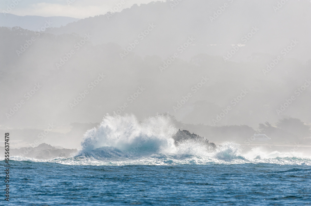 A giant wave is breaking at a cliff in Monterey Bay.
