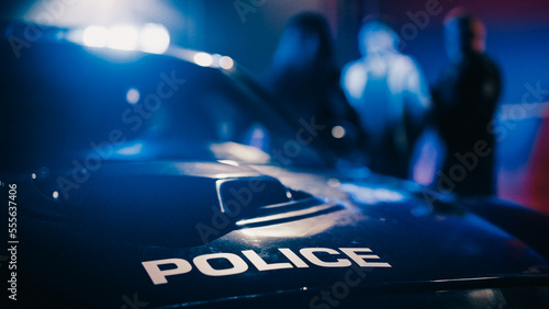 Cinematic Focus on Patrol Car: Two Police Officers Arrest Suspect, Put Him in Vehicle. Officers of the Law Handcuff Dangerous Criminal on Dark City Street. Cops Fight Crime. Documentary Shot