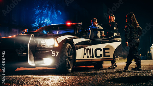 Two Police Officers Arrest Suspect, Put Him in Patrol Сar. Officers of the Law Handcuff Dangerous Criminal on Dark City Street. Cops Arresting Felon, Fight Crime. Cinematic Documentary photo