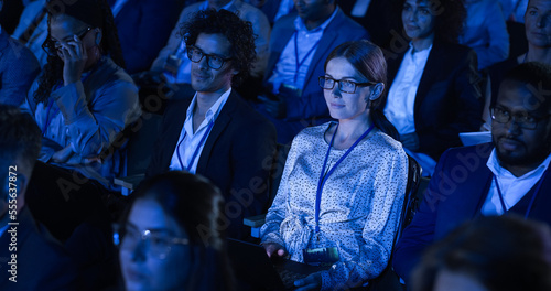 Beautiful Woman Sitting in Crowded Audience at a Business Conference. Female Delegate Using Laptop to Take Notes. Manager Watching Inspirational Entrepreneurship Presentation About Developing Markets. photo