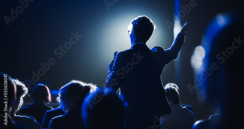 Fotografia Backview of a Stylish Young Businessman in a Dark Crowded Auditorium at a Startup Summit