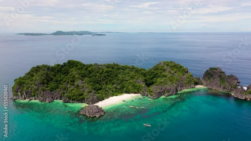 Tropical island with a white sandy beach. Tropical landscape:Matukad Island with beautiful beach and tourists by turquoise water view from above. Caramoan Islands, Philippines. Summer and travel photo