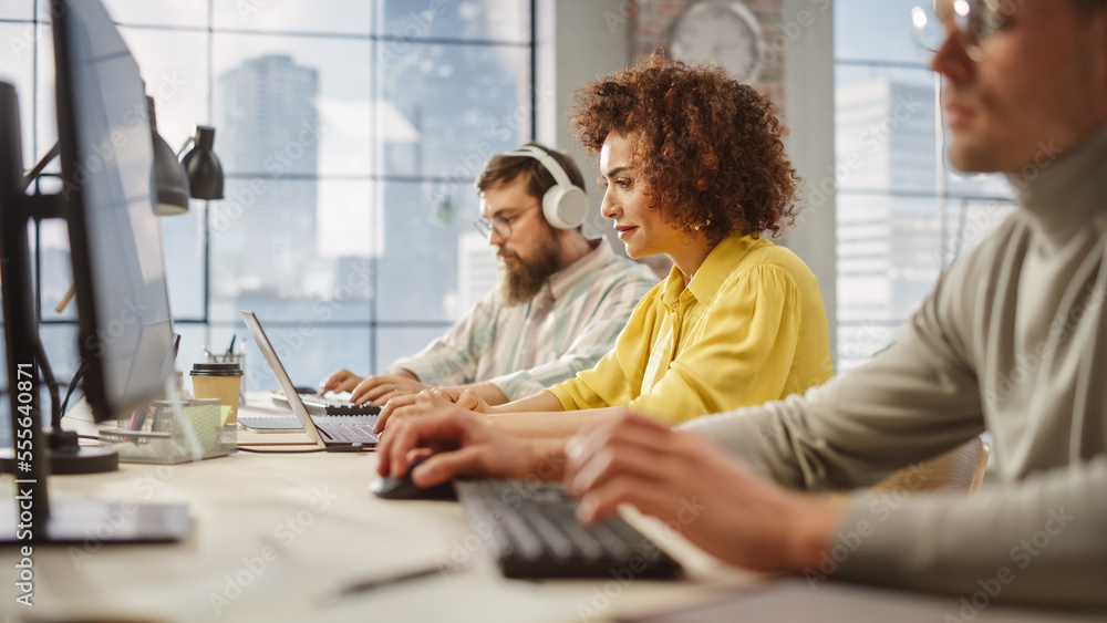 Portrait of Biracial Creative Young Woman Working on Computer in Bright Busy Office. Female Manager Smiling, Having Productive Day. People Working in the Background. Portrait of Biracial Creative Young Woman Working on Computer in Bright Busy Office. Female Manager Smiling, Having Productive Day. People Working in the Background.