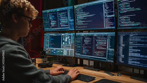 Young Caucasian Man Writing Code on Professional Six Monitors Setup in Dark Office. Male Cyber Security Expert Controlling Digital Data Protection System in International Intelligence Agency.
