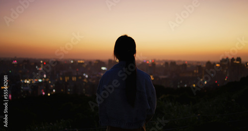 Silhouette of woman look at the city under sunset