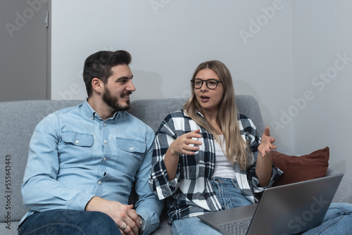 Young couple small business owners working from home. Married man and woman sitting on sofa in apartment work on new commercial ideas and strategy for web site and company they own.