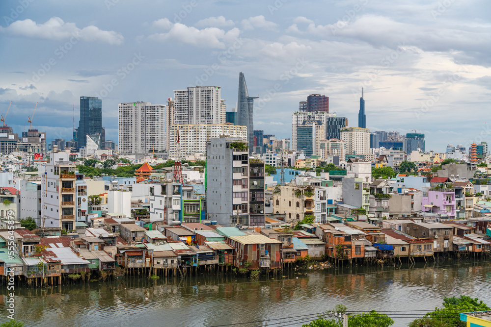 HO CHI MINH, VIETNAM - December 3, 2022: Slum wooden house on the Saigon river bank, in front of modern buildings in ho chi minh city. View to district 1, see Bitexco tower, Landmark 81. HO CHI MINH, VIETNAM - December 3, 2022: Slum wooden house on the Saigon river bank, in front of modern buildings in ho chi minh city. View to district 1, see Bitexco tower, Landmark 81.