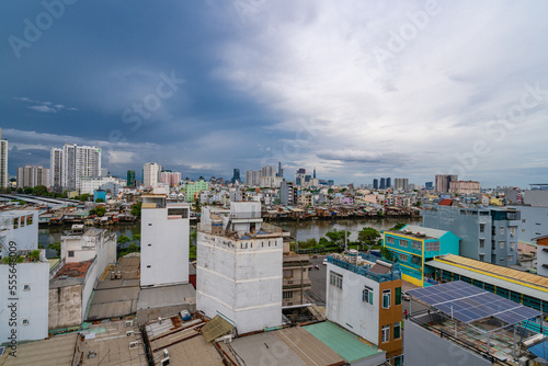 HO CHI MINH, VIETNAM - December 3, 2022: Slum wooden house on the Saigon river bank, in front of modern buildings in ho chi minh city. View to district 1, see Bitexco tower, Landmark 81. © Quang Ho