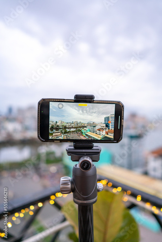 Close-up smartphone on tripod capturing night cityscape timelapse. Mobile photography or videography concept.