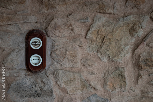 Fotografie Enchufe e interruptor antiguos sobre pared de piedra