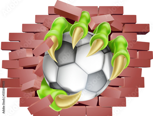A soccer football ball claw breaking through a wall