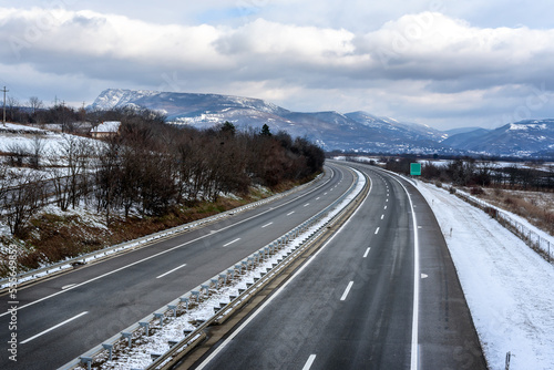 Silent freeway road in snowy winter season. Asphalt highway background. Winter Landscape with snowy fields