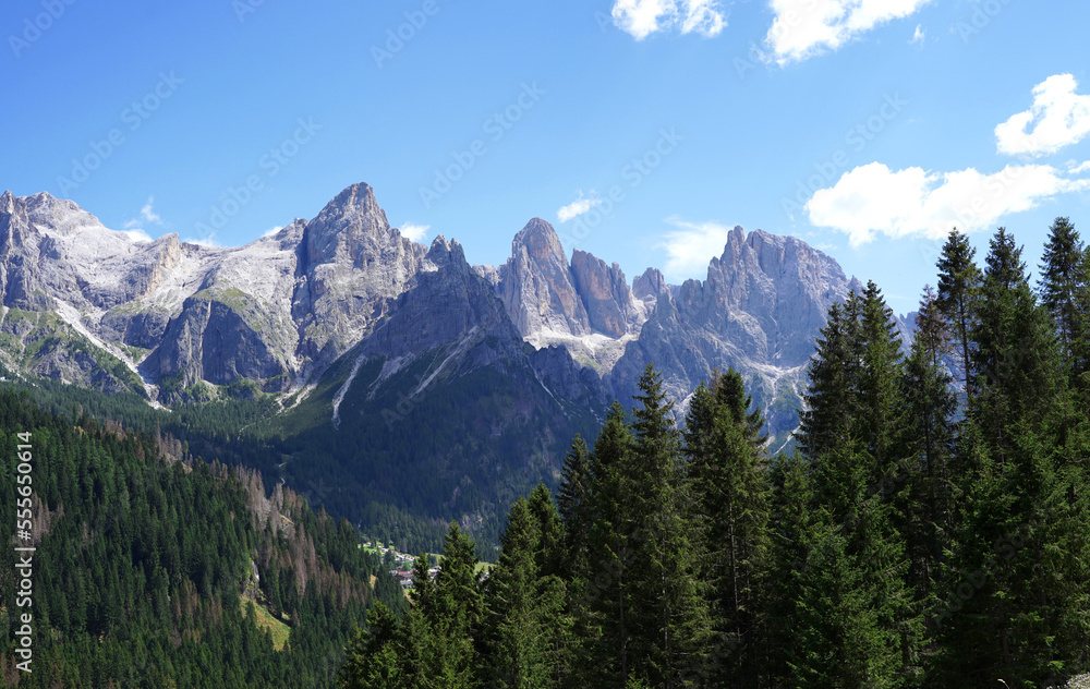Panorama of Italian Dolomites. Grey huge rocks with green trees around and blue sky. Beautiful nature background. Panorama of Italian Dolomites. Grey huge rocks with green trees around and blue sky. Beautiful nature background.
