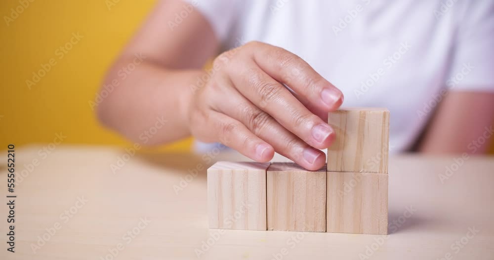 Hand putting wood cube on top of wood block stacking as step stair.business growth to success. Slow motion Hand putting wood cube on top of wood block stacking as step stair.business growth to success. Slow motion