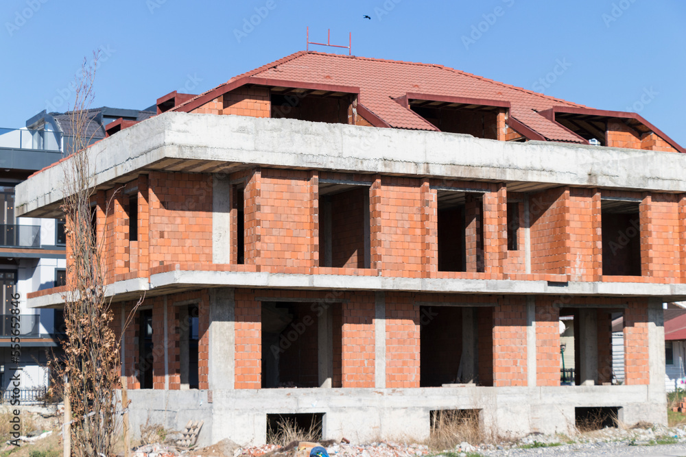 two-story apartment roof under construction and red-tiled red bricks