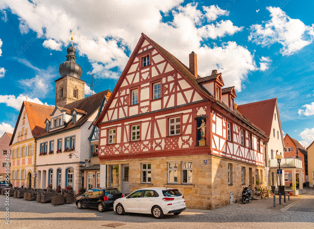 Sattlertorstrasse with old historic traditional German half timbered houses and St Martin church tower in the background with blue sky, Forchheim, Germany