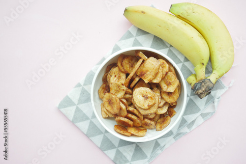  dry banana chips in a bowl on black tiles background 