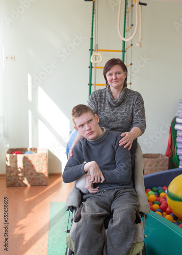 a boy with a disability in a rehabilitation center with special needs next to his mother.