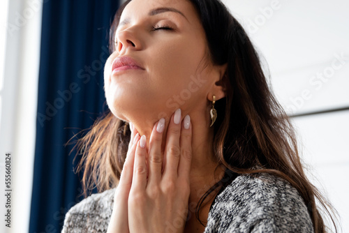 Young woman self examination thyroid gland photo