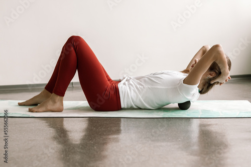 a beautiful girl does fitness in a bright hall with myofascial rolls