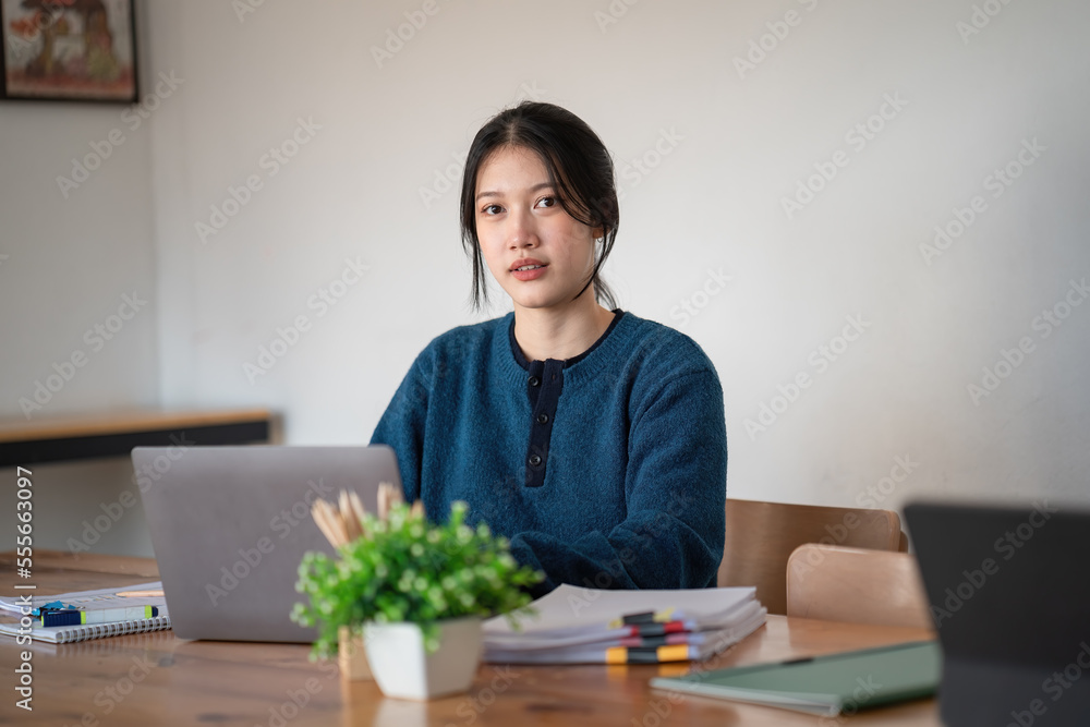 Beautiful Asian woman working on a laptop at work. She looked straight at the camera and showed confidence. Beautiful Asian woman working on a laptop at work. She looked straight at the camera and showed confidence.