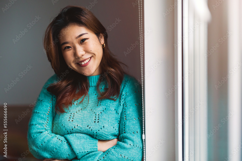 Young woman standing at a window in a home looking at a camera
Young woman standing at a window in a home looking at a camera
