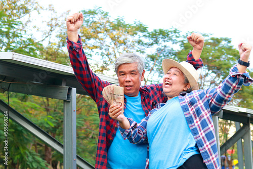 Asian elderly couple farming agriculture smiling happy holding Thai baht as income from agriculture Fototapeta