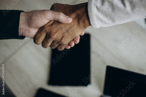 Two man colleagues shaking hands at the office