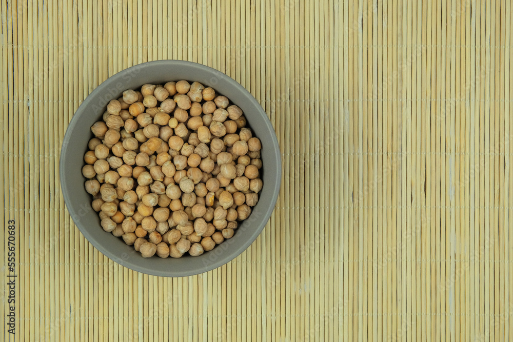 Chickpeas in bowl on a straw background. Vegetarian organic product. Vintage view. Top view. Copy space. Chickpeas in bowl on a straw background. Vegetarian organic product. Vintage view. Top view. Copy space.