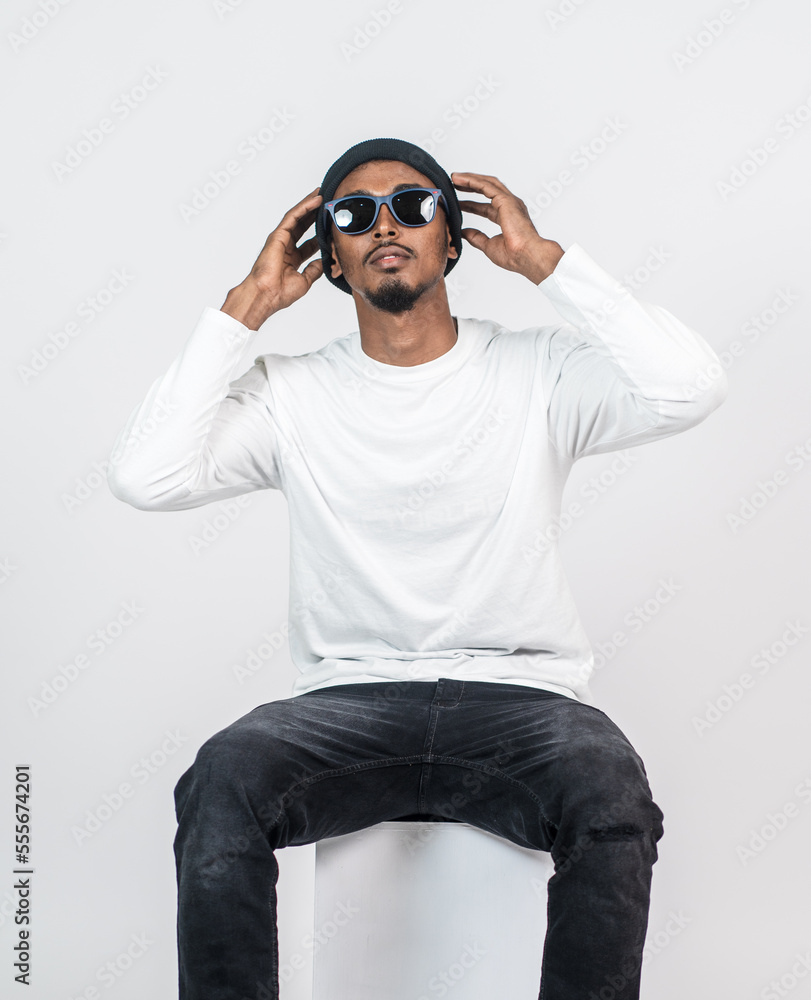 An african man white blank shirt sitting on the top of a chair with white background An african man white blank shirt sitting on the top of a chair with white background