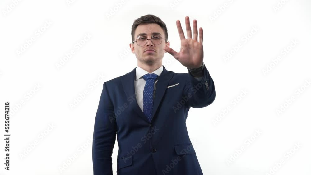 Young male businessman in a suit making a stop sign with his hand raised. The concept of prohibition or denial. Young male businessman in a suit making a stop sign with his hand raised. The concept of prohibition or denial.