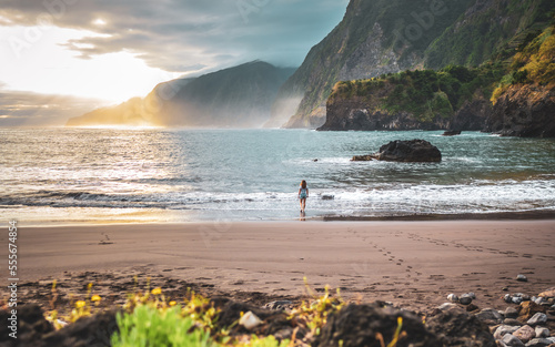 Woman walking on beautiful beach and enjoying the atmospheric morning atmosphere. Seixal beach, Madeira Island, Portugal, Europe. photo