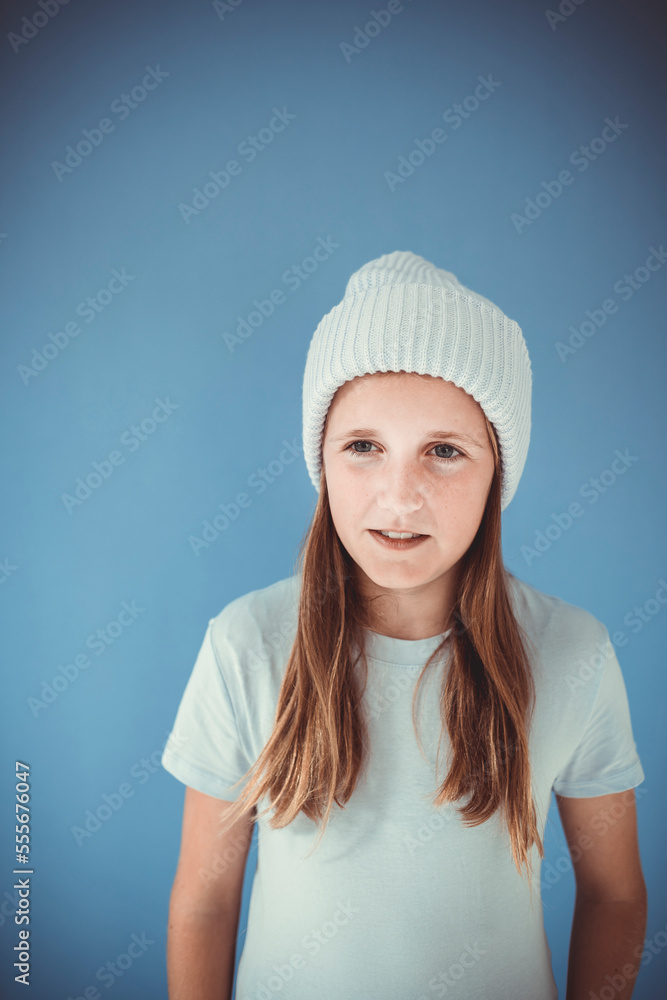 cool and pretty girl with winter wool beanie is standing in front of blue background and making grimaces, faces cool and pretty girl with winter wool beanie is standing in front of blue background and making grimaces, faces