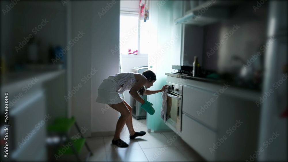 Young woman checking oven at kitchen. Candid casual person cooking food Young woman checking oven at kitchen. Candid casual person cooking food