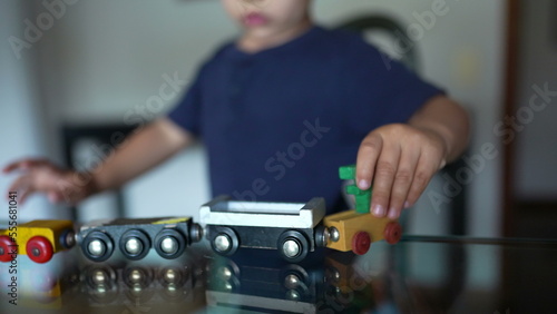Small boy playing with toys. Child plays alone at home with traditional wooden train toy