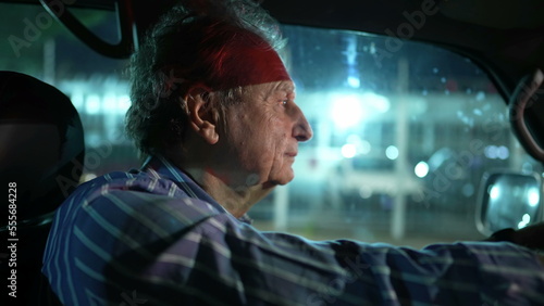 Older man driving at night in city. Profile closeup face of mature senior male driver person drives in evening © Marco