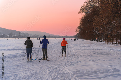 At sunset on a frosty winter evening, the townspeople go skiing, walking their dogs. Active holidays in winter, health prevention, a large snowy field in Krakow on Christmas Eve, real is radical